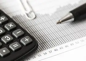 Close-up of a calculator and pen on a bar graph, representing finance and accounting.